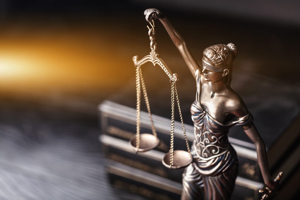 Bronze scales of justice with books in background