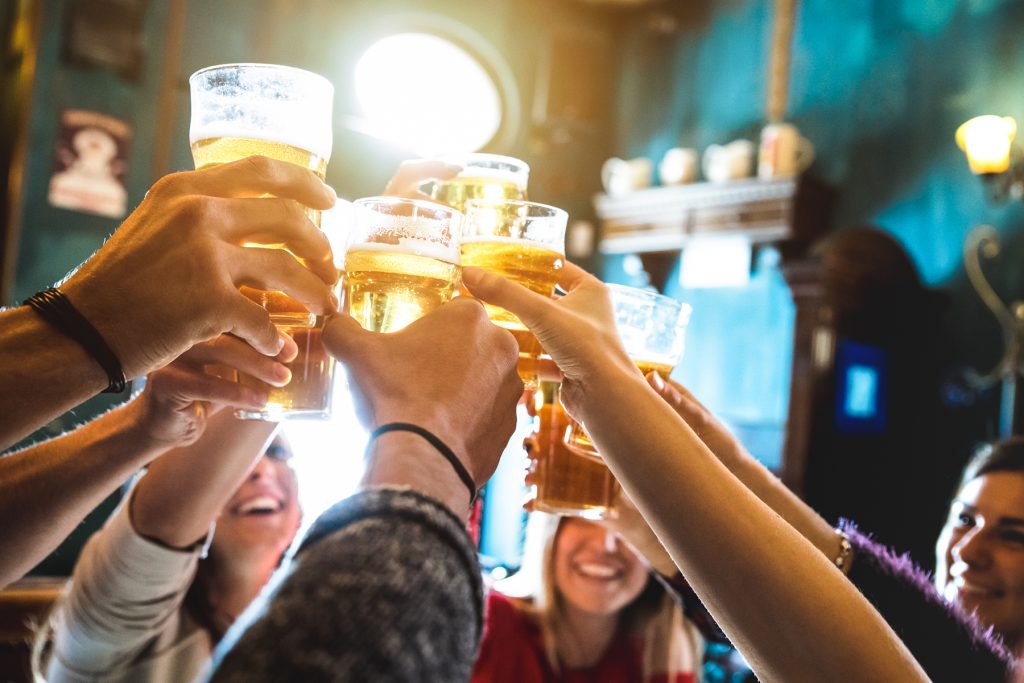 6 people in a bar cheersing their beers together