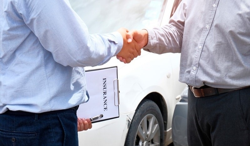 Negotiate with insurance companies. Two men in front of car shaking hands