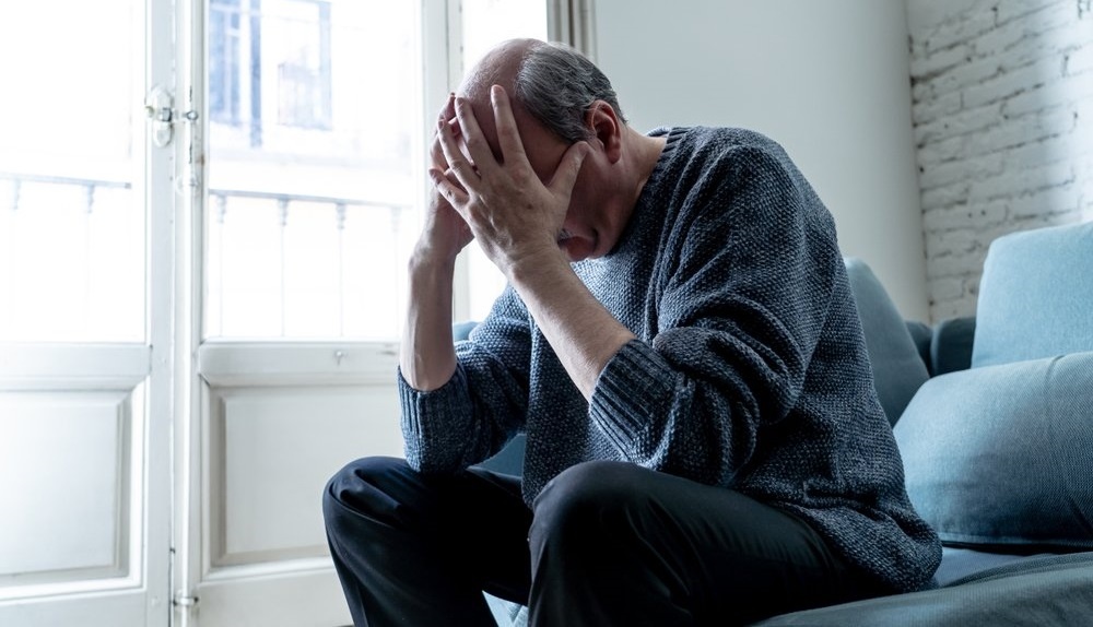 Man sitting on a couch experiencing pain and suffering in Rhode Island